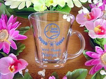 「テニスサークルのマーク」「With thanks、名前」を彫刻した、卒業する先輩への贈り物用のガラス製ティーカップ