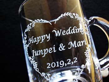 結婚祝い用のガラス製マグカップ側面に彫刻した、「お祝いメッセージ、新郎と新婦の名前」のクローズアップ画像