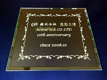 「会社の名前とマーク、10th Anniversary、会社設立日」を彫刻した、お取引先の会社へ贈る周年祝い用のガラス盾