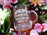 「○○中学校 平成元年度卒業生一同より」を彫刻した、同窓会の記念品用のガラス製マグカップ