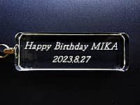 「Happy Birthday、贈る相手の名前、誕生日の日付」を長札型のガラス部に彫刻した、誕生日プレゼント用のキーホルダー