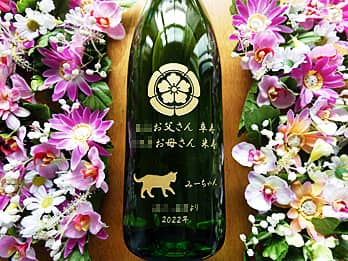 「家紋、贈る相手の名前と年齢、猫のイラスト、贈り主の名前」を一升瓶の側面に彫刻した、長寿祝い用の日本酒