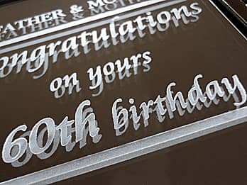 還暦祝い用の写真立て（ブックタイプ）の鏡の部分に彫刻したお祝いメッセージ「Congratulations on your 60th birthday」のクローズアップ画像