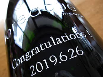 開店祝い用のワインボトル側面に彫刻した、「店名、お祝いメッセージ、日付」のクローズアップ画像