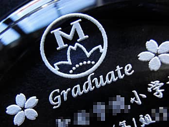 卒業記念品用のガラス製ペーパーウェイトの接地面側に彫刻した「校章、メッセージ、学校名」のクローズアップ画像