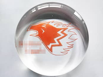 彫刻したマークをオレンジに着色加工したガラス製ペーパーウェイト