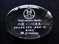 「校章」と「With sincere thanks、○○先生、令和元年度卒業生 保護者一同」を彫刻した、担任の先生へ贈るガラス製ペーパーウェイト