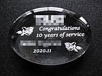 「会社のロゴ」と「Congratulations 10years of service、永年勤続者の名前、日付」を彫刻した、永年勤続のお祝い品用のガラス製ペーパーウェイト