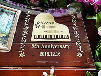 「ロゴマーク」「5th anniversary」を彫刻した、ピアノ教室の周年祝い用のガラス製写真立て