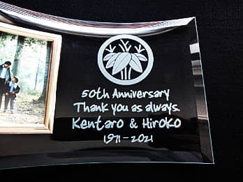 「家紋」と「50th Anniversary. Thank you as always. 両親の名前」を彫刻した、両親の金婚式祝い用のガラス製写真立て