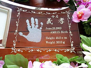 赤ちゃんの手形を彫刻した、出産祝い用のガラス製フォトスタンド
