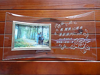 「祝 開院10周年、○○クリニック、スタッフ一同」を彫刻した、周年祝い用のガラス製写真立て