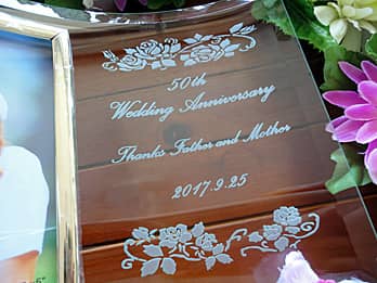 「お祝いメッセージ、両親の名前、結婚記念日の日付」を彫刻した、両親の結婚記念日祝い用のガラス製写真立て