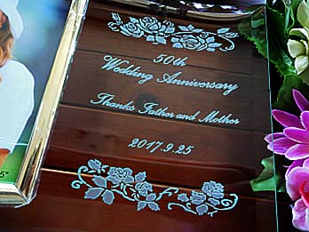 「お祝いメッセージ、贈る相手の名前、日付」を彫刻したガラス製の写真立て