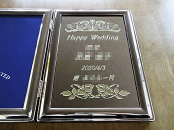 「Happy wedding、新郎と新婦の名前、挙式日」を彫刻した、結婚祝い用のブックタイプの写真立て
