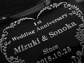 結婚記念日祝い用のガラス製写真立てに彫刻した、「1st wedding anniversary、旦那様と奥さまの名前、結婚記念日の日付」のクローズアップ画像