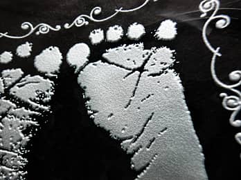出産祝い用のガラス製写真立てに彫刻した、「赤ちゃんの足形」のクローズアップ画像