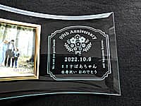 「99th Anniversary ○○ばあちゃん白寿祝い おめでとう」を彫刻した、白寿祝い用のガラス製写真立て