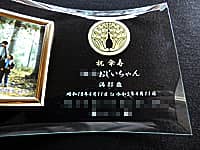 「家紋」と「祝傘寿 ○○おじいちゃん 満80歳、誕生日の日付、家族全員の名前」を彫刻した、傘寿祝い用のガラス製写真立て