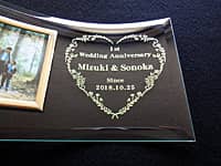 「1st wedding anniversary、旦那様と奥様の名前、日付」を彫刻した、紙婚式のお祝い品用のフォトスタンド