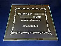 「株式会社○○、10th anniversary」を彫刻した、お取引先への周年祝い用のガラス盾