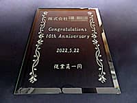 「株式会社○○ Congratulations 10th anniversary 従業員一同」を彫刻した、会社の10周年祝い用のガラス盾