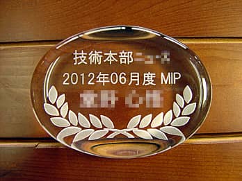「技術本部○○賞、2012年6月度MIP ○○殿」を彫刻した、賞品用のガラス製ペーパーウェイト