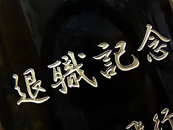 定年退職祝い用の日本酒の一升瓶側面に彫刻した、「退職記念」のクローズアップ画像