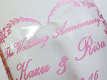 ピンクに着色した、ガラス花器の側面に彫刻した文字のクローズアップ画像