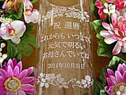 「祝 還暦、元気で明るいお母さんでいてね」を側面に彫刻した、母親への還暦祝い用のフラワーベース