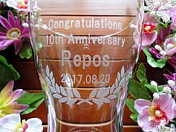 「Congratulations! 10th anniversary、店名」を側面に彫刻した、お店の周年祝い用のフラワーベース