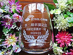 「保育園のマーク、第2期卒園記念、卒園児保護者一同より」を側面に彫刻した、保育園に寄贈する卒園記念品用のガラス花瓶