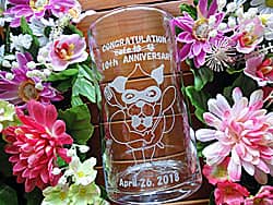 「Congratulations! 10th anniversary、お店のキャラクター」を側面に彫刻した、カフェの周年祝い用のガラス花瓶