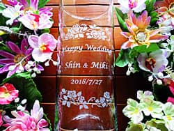 新郎新婦の名前とお祝いメッセージを彫刻した、結婚祝い用のガラス花器