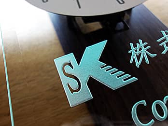 掛け時計の前面ガラスに彫刻したロゴマークのクローズアップ画像