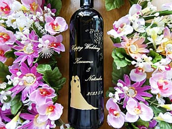 「新郎新婦のシルエットのイラスト」と「Happy Wedding、新郎と新婦の名前、結婚式の日付」をボトル側面に彫刻した、結婚祝い用のワイン