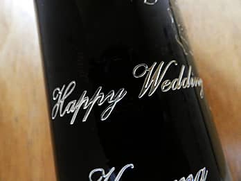 結婚祝い用のワインのボトル側面に彫刻した、「Happy Wedding」のクローズアップ画像