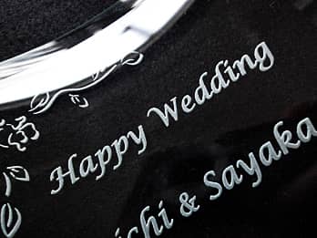 結婚祝い用のガラス製写真立てに彫刻した、「Happy Wedding、新郎と新婦の名前」のクローズアップ画像