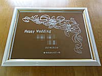「Happy wedding 新郎と新婦の名前 結婚式の日付」を額縁に入った鏡に彫刻した、結婚祝い用のウェルカムボード